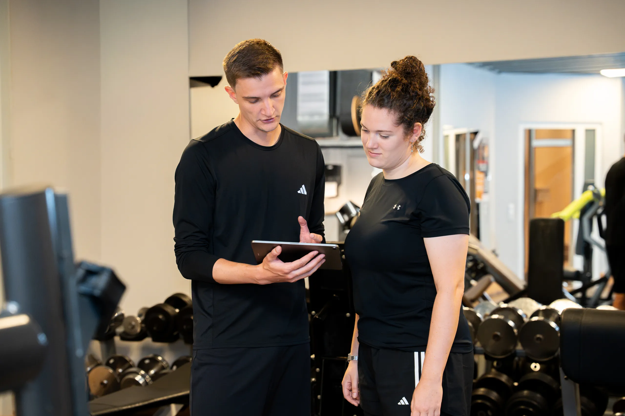 Trainer begleitet ein Mitglied beim freien Training